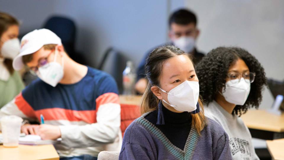 Masked students listen attentively during a class.