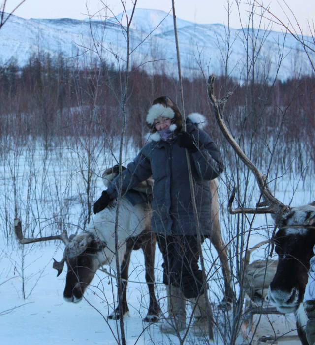 Olga Ulturgasheva poses with a reindeer in an arctic setting.