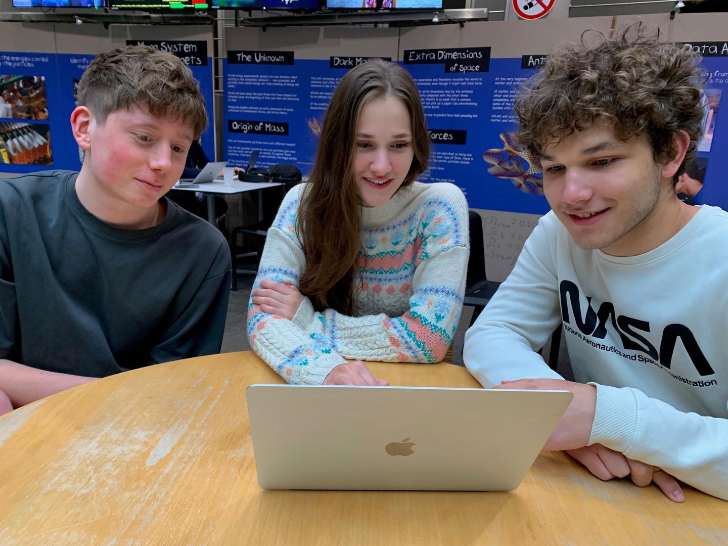Three students around a laptop