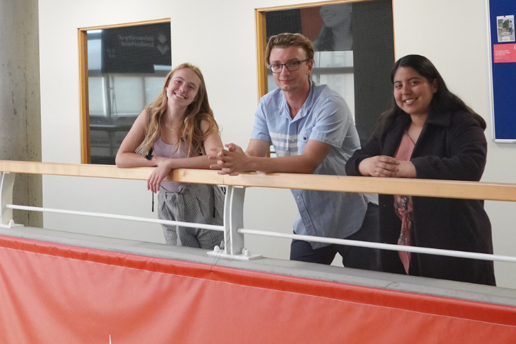 Three interns at a balcony smiling