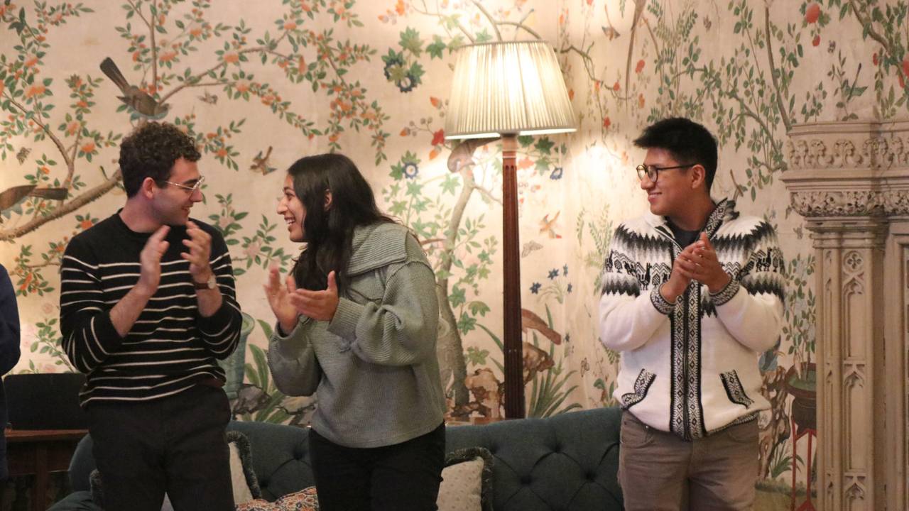 Students clap in a wallpapered room
