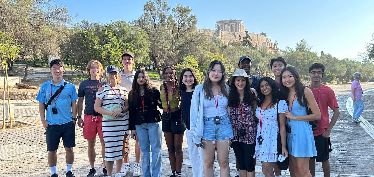 A group shot of about a dozen students and their instructor near the Acropolis in Greece.
