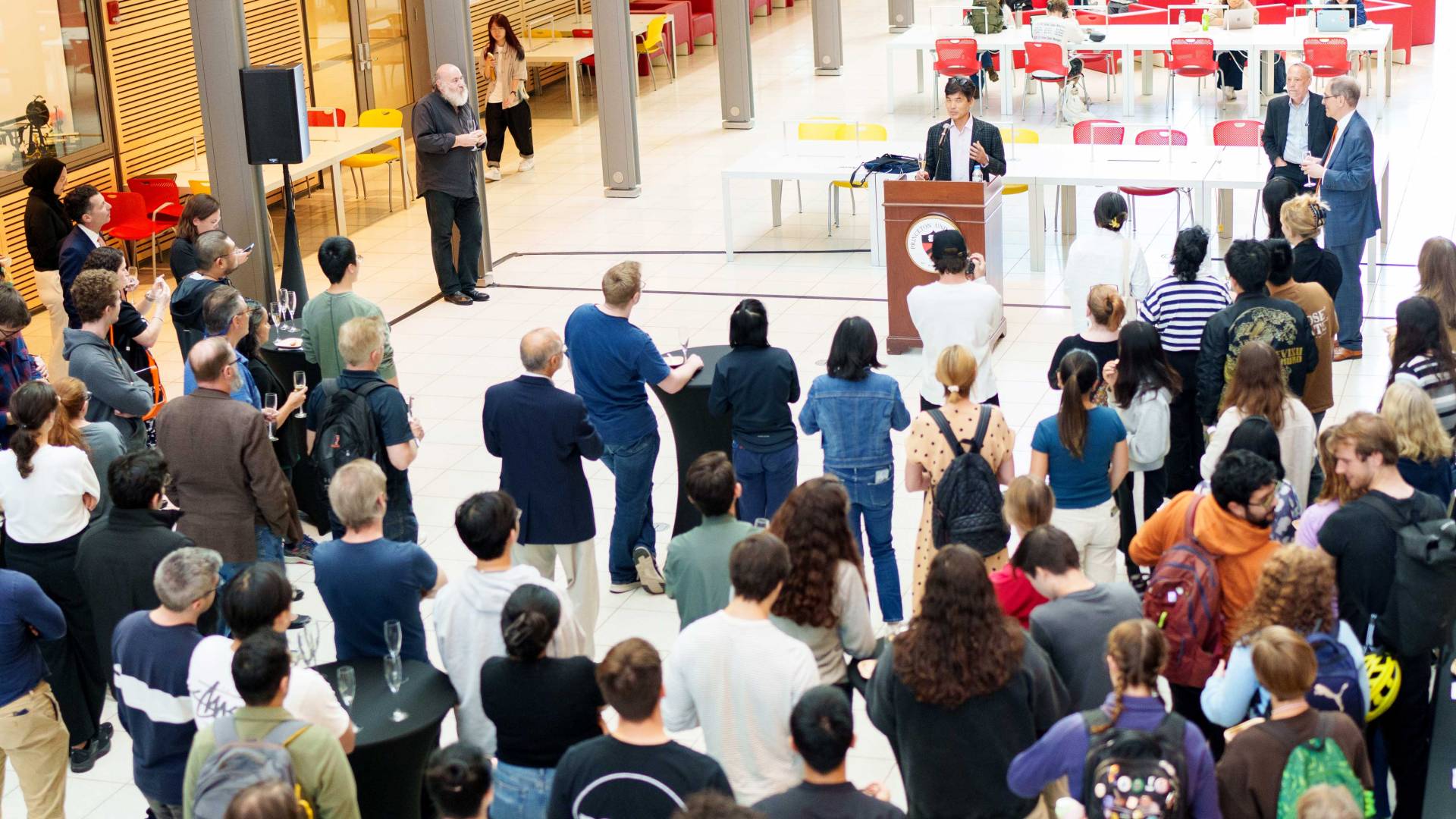 An atrium filled with people; a speaker at a lectern 