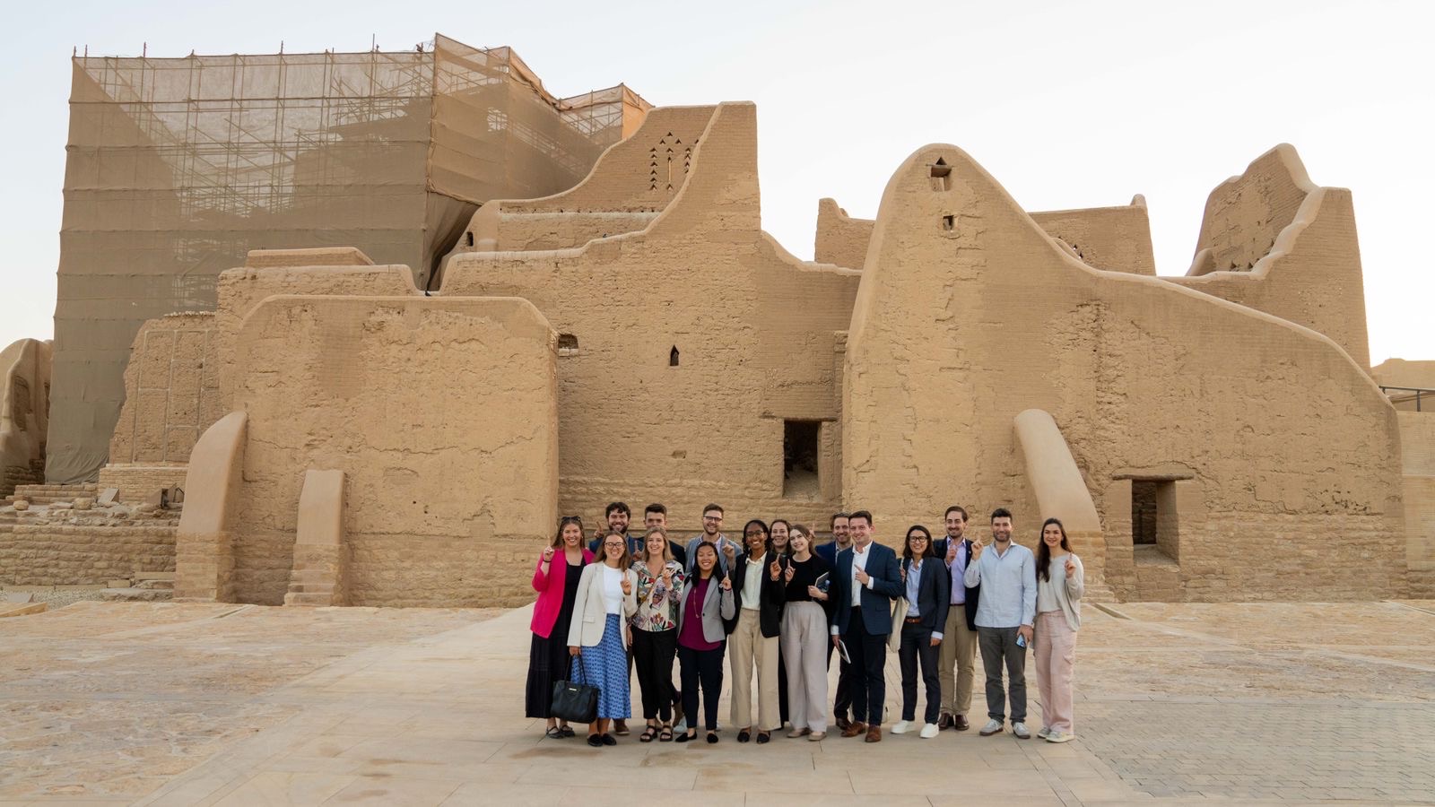 An image of SPIA students standing behind a brown clay building under restoration