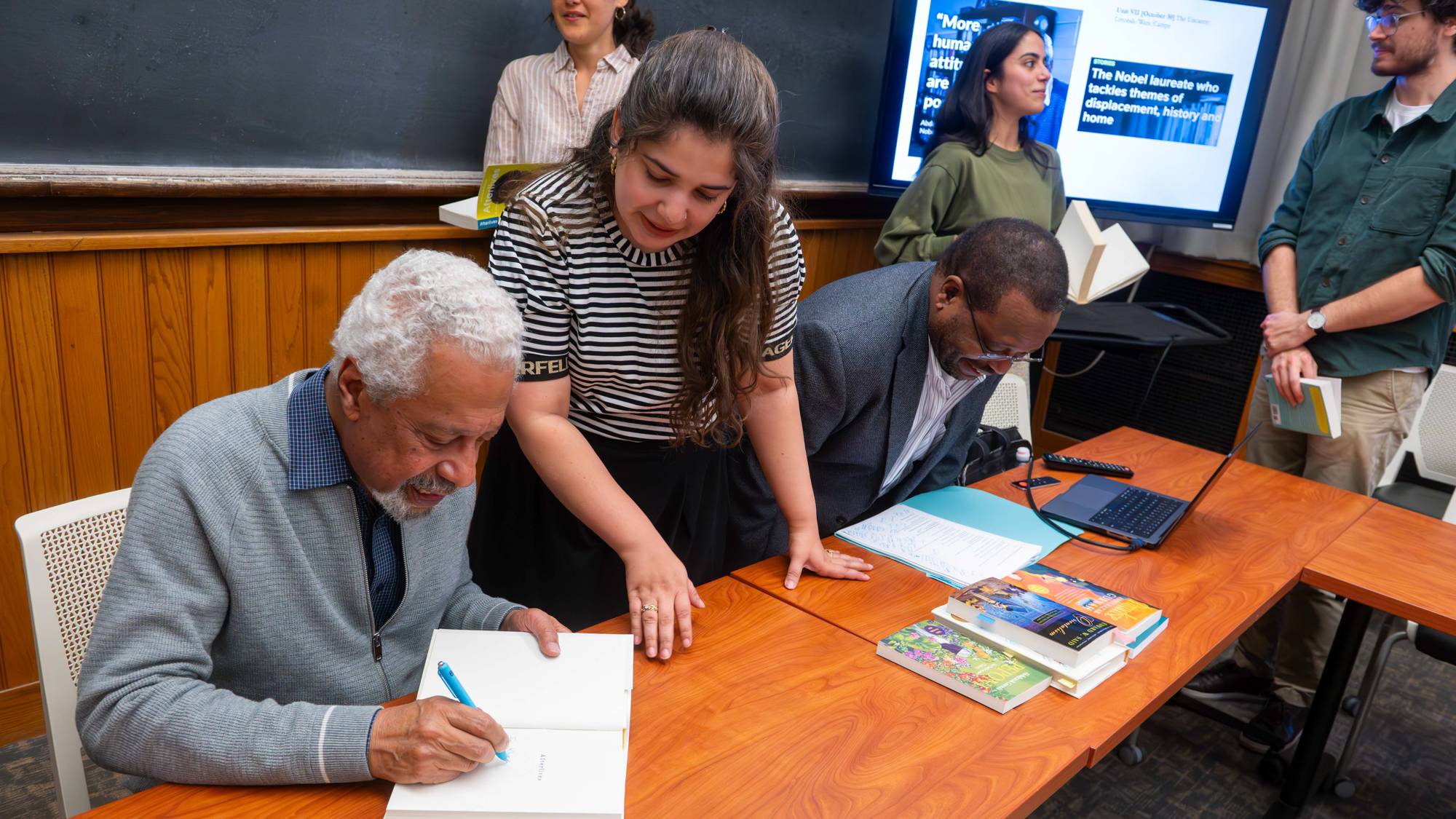 An image of Second year graduate student looking at Gurnah signing her personal copy of "Afterlives"