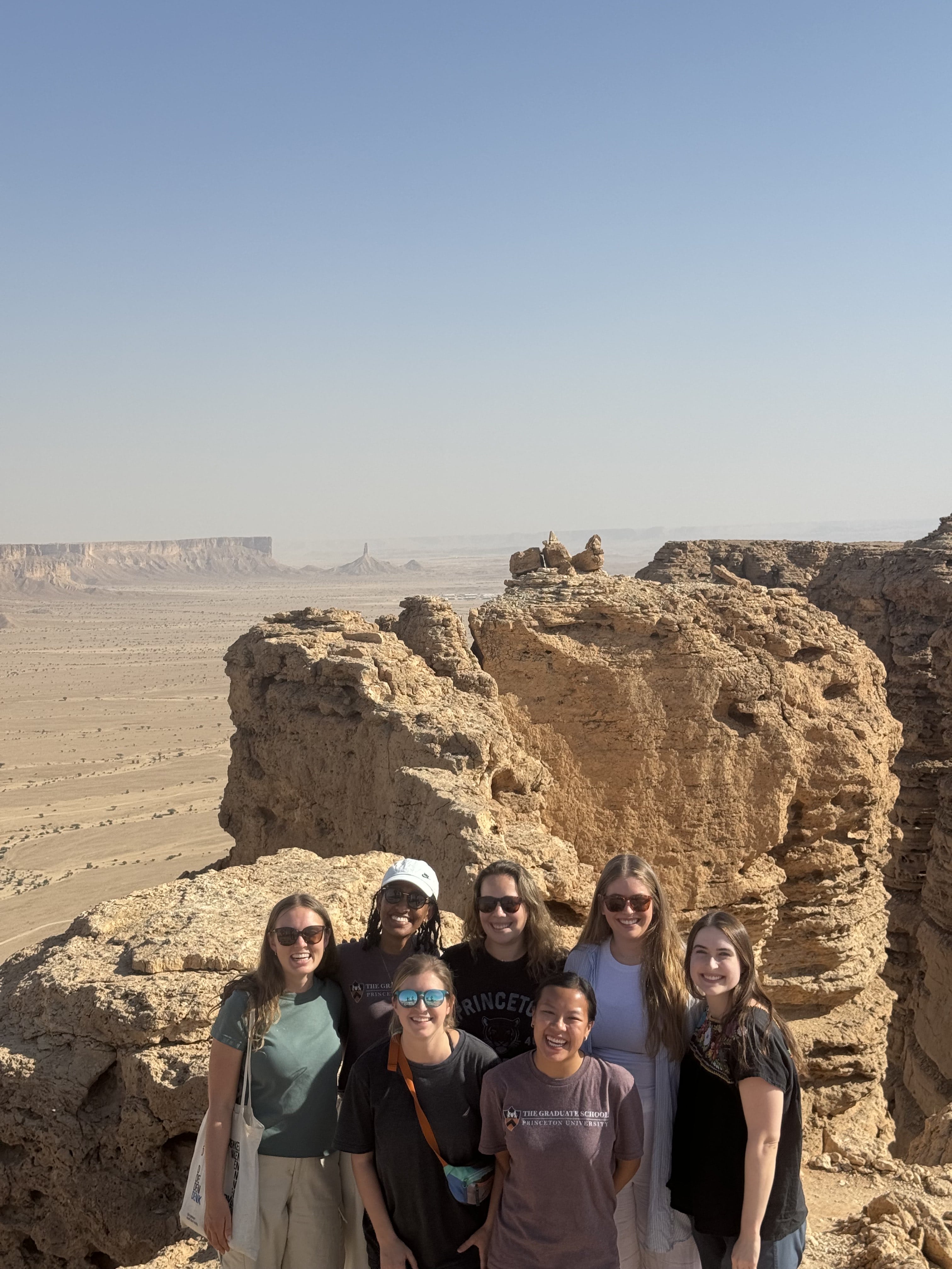 SPIA students smiling in the desert behind a sandy rock