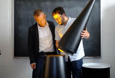 Two men peer into a lighted up sphere.