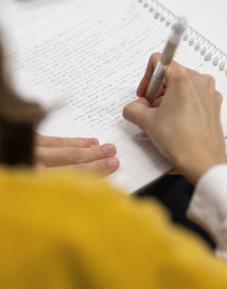 A student takes notes during a presentation