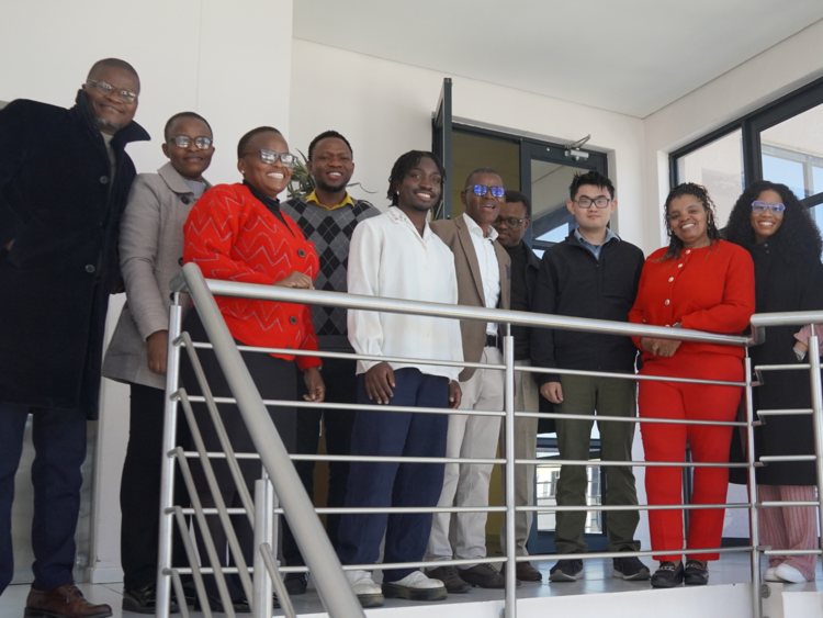 group shot of about a dozen people by a stair case