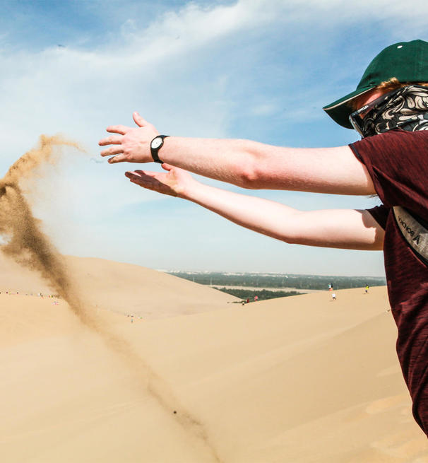 A student throws sand in the desert
