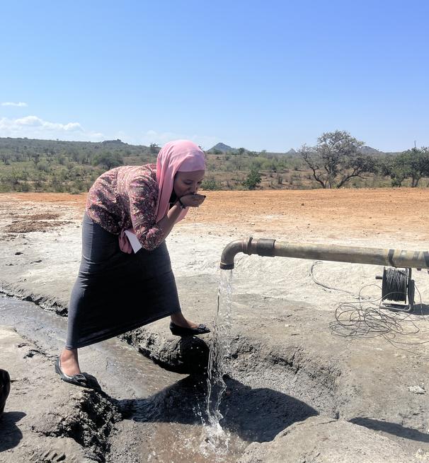 a young girl drinking water from a tap at Mpala