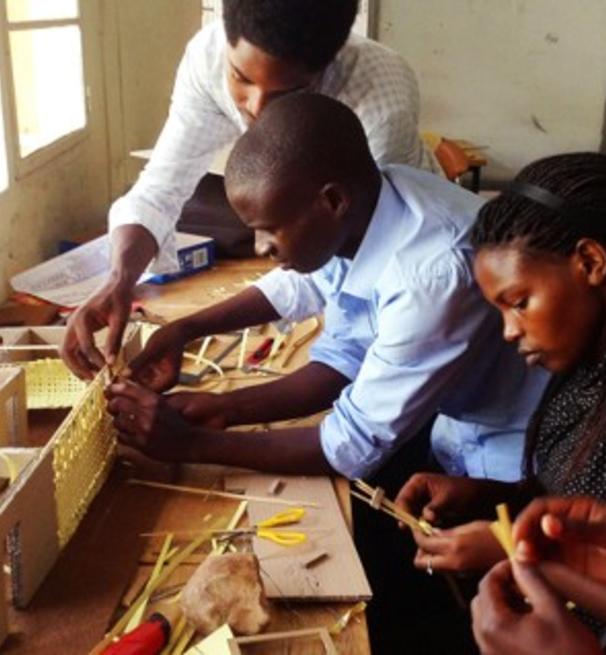 A group of four people building a housing model