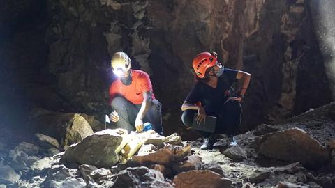 Two scientists excavate in a dark cave
