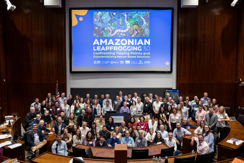 A group is assembled in a Princeton bowl auditorium under a projector showing the Amazonian Leapfrogging 3.0 promotional poster