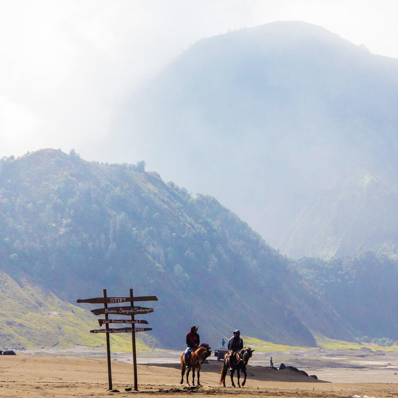 Two figures on horseback against an indonesian mountainous backdrop.