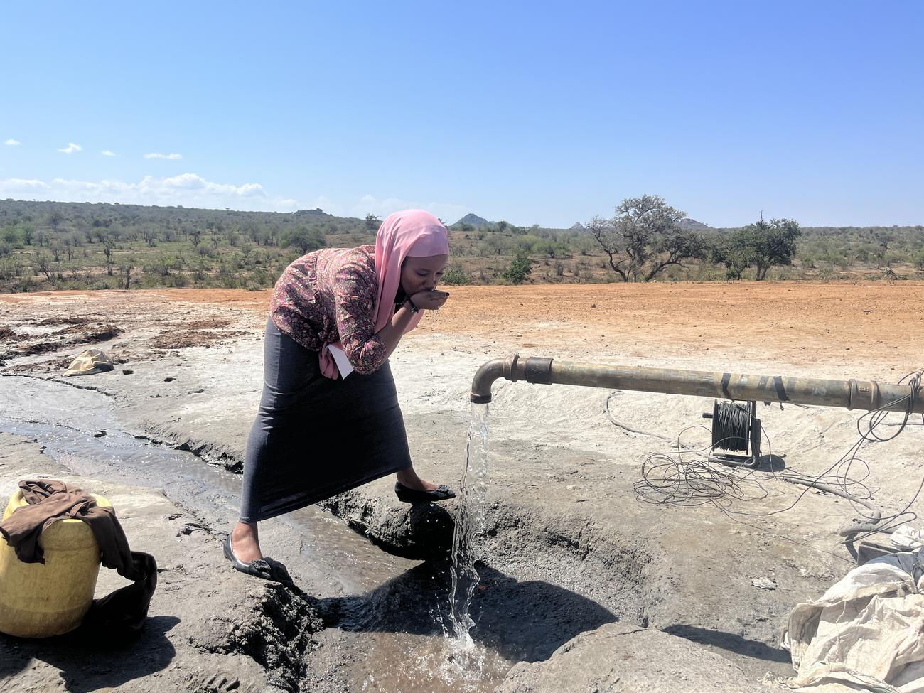 a young girl drinking water from a tap at Mpala