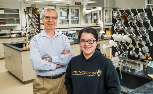 Professor with arms crossed in the back and researcher wearing Princeton hoodie in the front. Both posing and smiling for the camera.
