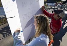 two students sign a large posterboard