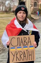 A student holds a sign in Ukrainian that reads "Glory to Ukraine."