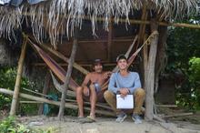Salama sitting with Ederardo Perez, a Colombian fisherman, in a thatched hut 