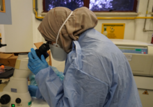 A student in scrub looks through a microscope