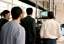 The group looks over a circuit board model. 