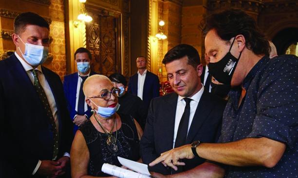 Four people stand talking around a sheet of paper. Ukrainian President Zalenskyy is among them.