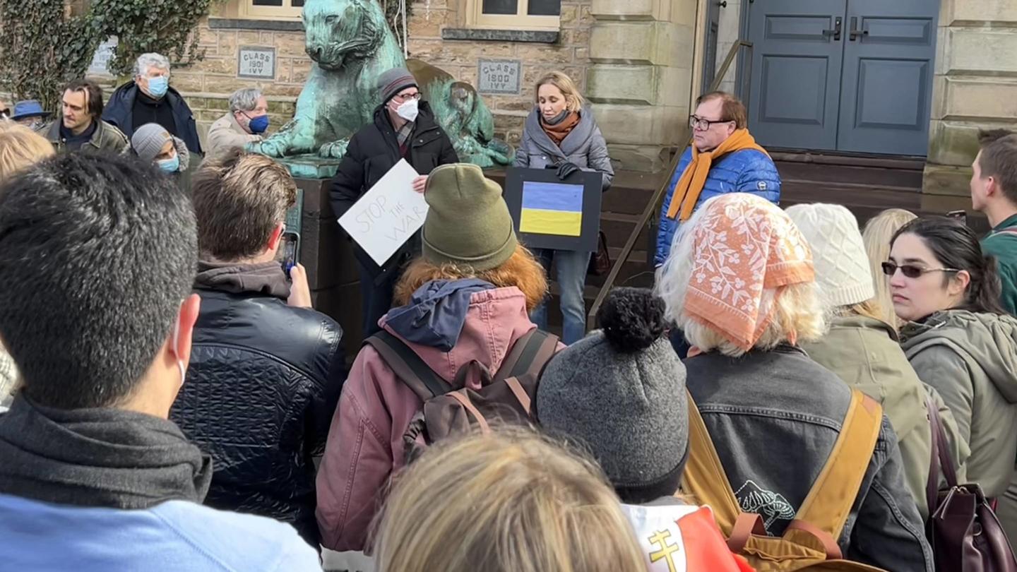 A group of people in winter clothing gather at the steps of Nassau Hall.