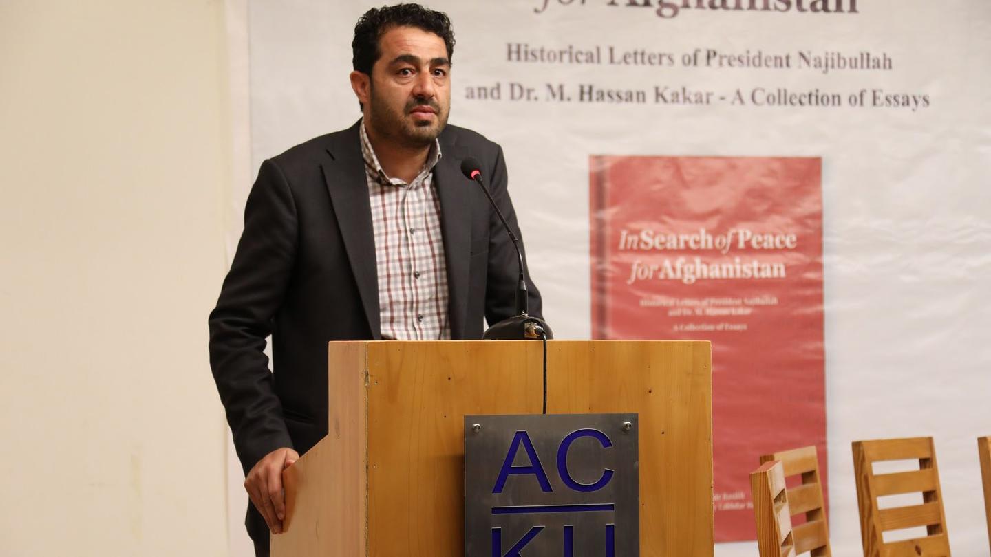 Abdul Wahid Wafa standing behind a podium at an event.