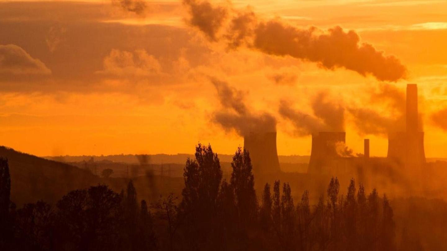 Nuclear power plants in silhouette against an orange sunset