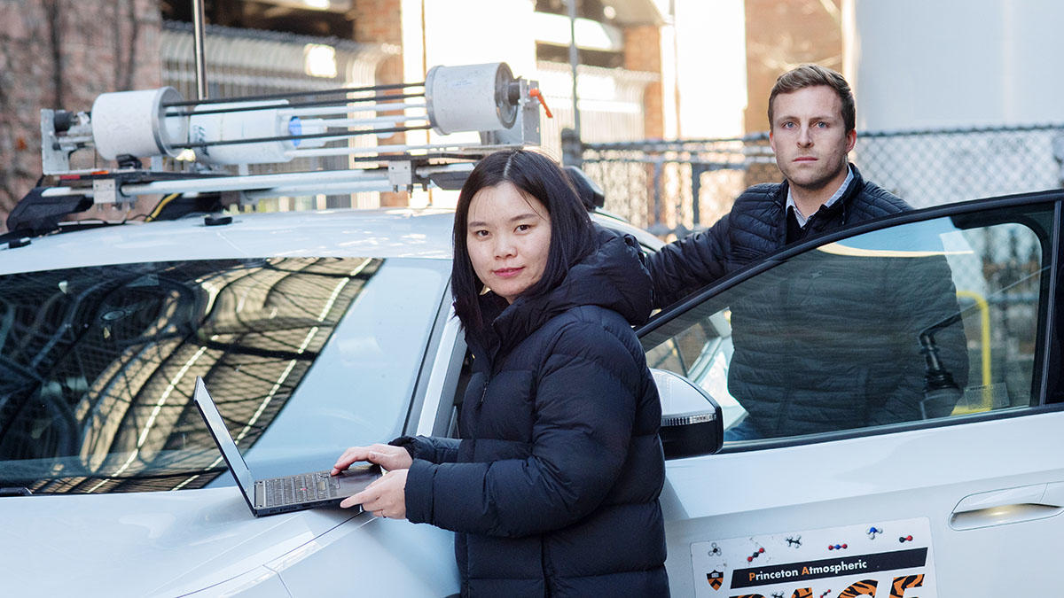 Two researchers next to a car with a laptop