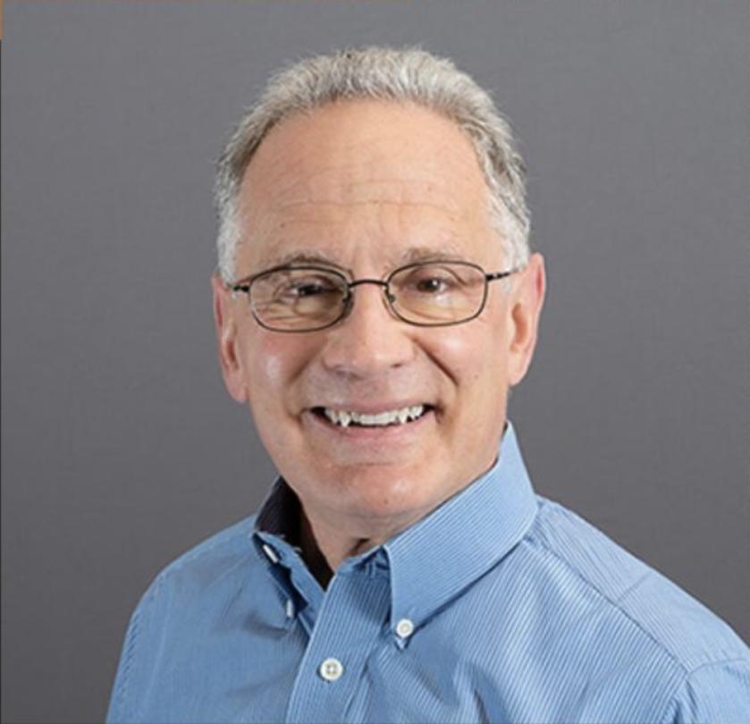 A headshot of David Wilcove wearing a blue dress shirt and smiling