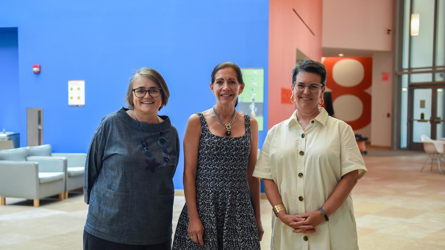 An image of three ladies standing and smiling together