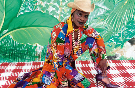 Artist appears in self portrait wearing brightly colored clothing