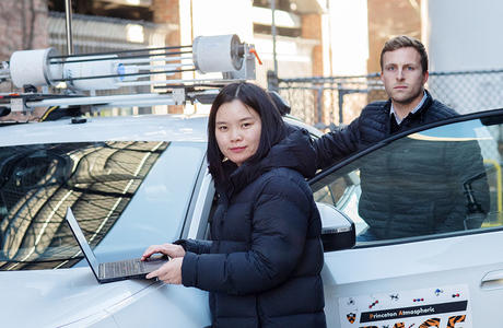 Two researchers next to a car with a laptop