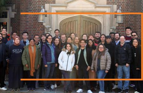 A large group of students pose outside of a Princeton building