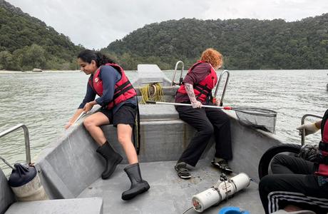 Two students wearing red life jackets on a boat