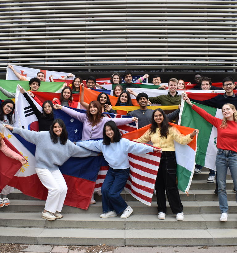 A group of students in front of the Simpson international building holding the flags of their home countries
